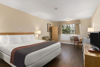 Relax in this cozy space with a comfortable sofa, flat-screen TV, and a door leading to a bedroom with a bed.