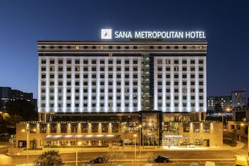 Un hotel moderno con fachada de vidrio, varias banderas y una entrada destacada.