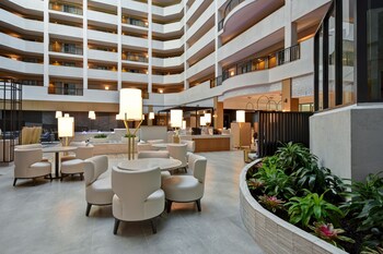 Un vestíbulo de hotel de varios niveles con un atrio central, varias zonas de comedor y una piscina.