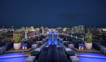 A rooftop bar with a city skyline view, featuring seating areas and decorative elements.