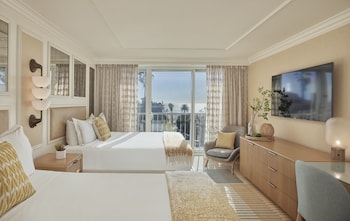 Relax in a stylish room with two beds, a seating area, and a large window offering ocean views.