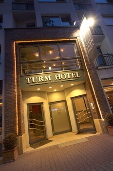 Exterior del Hotel Turm con fachada moderna, puertas dobles y un balcón.