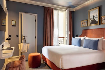 A neatly arranged bedroom with a bed, pillows, a bedside table, a lamp, and a book.