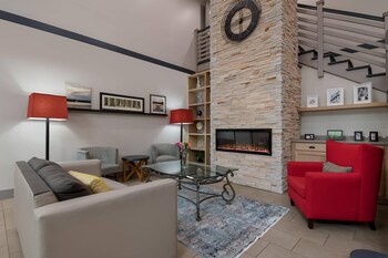 A spacious lobby with a staircase, a reception desk, and a seating area with a sofa and chairs.