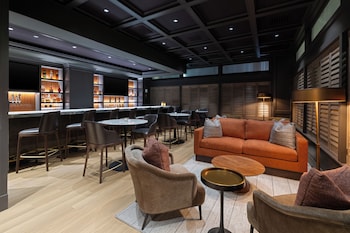 A modern lobby with leather sofas, armchairs, and a coffee table. There are books and a lamp on the coffee table.