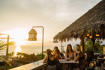 Un resort con bungalows sobre el agua, una pasarela de madera y un jardín acuático.