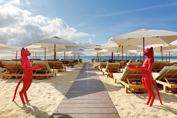 Un salon de plage avec une piscine, des chaises longues et une table dressée avec divers plats.