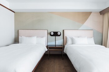 Un moderno vestíbulo de hotel con una larga mesa de comedor, varios arreglos de asientos y un sillón azul.