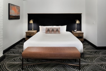 A spacious room with exposed wooden beams, a large chandelier, leather sofas, and a wooden cabinet.