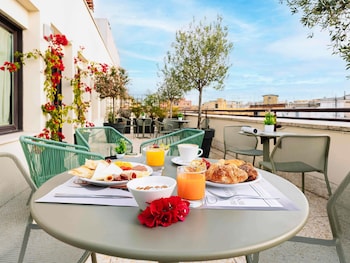 A balcony with a round table, two mesh chairs, a potted plant, and a cup.