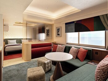 A modern hotel room with a bed, seating area, and a large window.