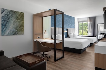 Two large beds in a stylish room with a geometric-patterned wall and a large window offering a view of the outdoors.