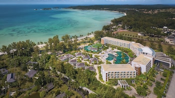 A resort with multiple swimming pools, palm trees, and beachfront views.