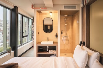 Enjoy a city view from the large window, with a comfortable bed and modern bathroom amenities.