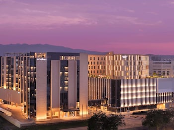 A modern hotel with a prominent tower, large windows, and a well-lit facade.