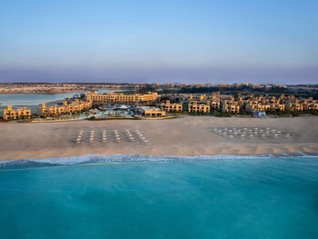 Relax by the serene pool surrounded by palm trees and a natural rock formation.