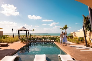 A modern outdoor pool area with lounge chairs and a view of the sea.