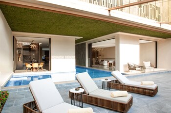 Une cour moderne agrémentée d’éléments aquatiques, d’un aménagement paysager aux formes géométriques et d’une architecture minimaliste.