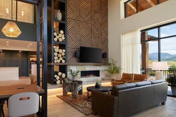 A spacious, well-lit interior with a high ceiling, large windows, and a variety of seating arrangements including sofas and tables.