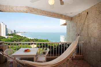 A beachside dining setup with tables set for two, surrounded by palm trees and ocean views.