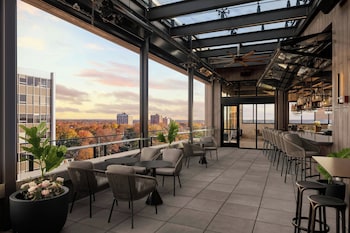 A rooftop terrace with modern outdoor seating, a fire pit, and a view of the cityscape.