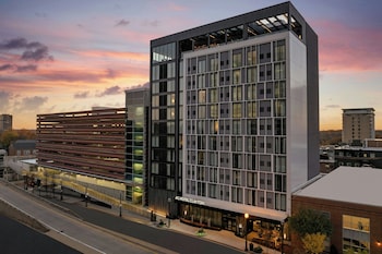 A rooftop terrace with modern outdoor seating, a fire pit, and a view of the cityscape.