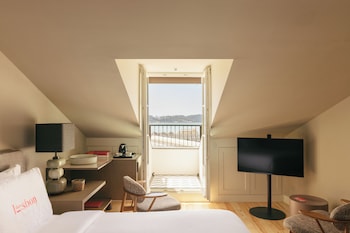 A room with a dining table and chairs, a lamp, and a view of a building with a dome through an open door.