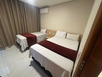 A bedroom with a bed, a desk, a chair, a mirror, and a wooden wardrobe.