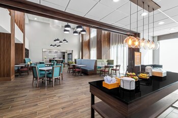 A modern hotel lobby with wooden flooring, seating areas, and a reception desk.