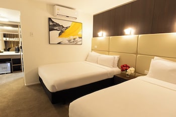 A modern hotel lobby with a reception desk, two chairs, a large window, and a staircase.