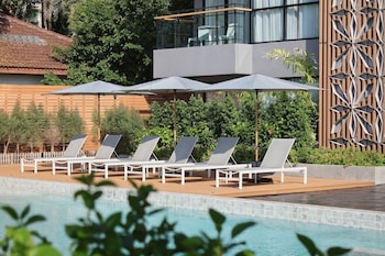 Zona de piscina con sillones reclinables y sombrillas, con vista a un puente y una masa de agua.
