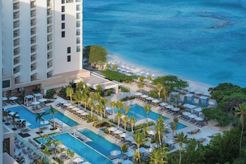 Un resort con varias piscinas, zonas de descanso y vistas al océano.