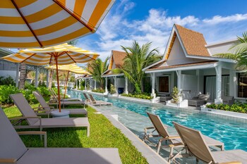 A modern house with a pool, surrounded by palm trees and greenery.
