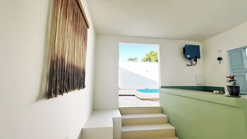 A modern outdoor pool area with a wooden deck, a staircase, and a dining area with chairs and tables.