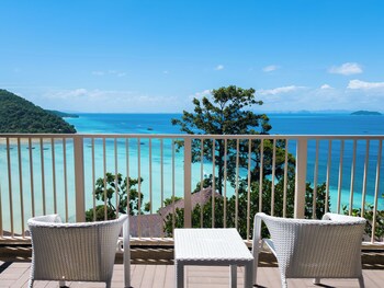 A resort with multiple bungalow-style accommodations surrounded by lush greenery, a swimming pool, and a dock with a boat.