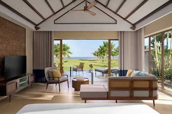 Un espace aménagé au bord de la piscine, avec des chaises longues, une petite table et une vue sur la piscine et les bâtiments du complexe hôtelier.