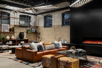 A modern bar area with a long counter, wooden chairs, and a seating area with sofas and a fire pit.