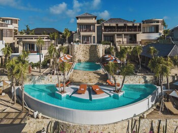 Un resort con piscina central, varias edificaciones y palmeras.