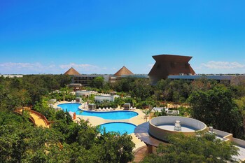 A resort with multiple swimming pools, a large central pool, and a distinctive pyramid-shaped building in the background.