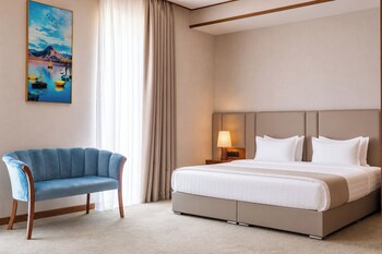 A modern hotel lobby with a reception desk, a sofa, and a large chandelier.