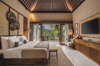 A room with a thatched roof, bamboo furniture, and a view of palm trees.