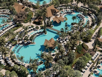 A resort with multiple swimming pools, a large building, and a view of the ocean.