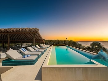 A clear blue swimming pool with a view of the ocean and palm trees.
