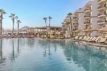 Un resort con varias piscinas, tumbonas y un gran crucero al fondo.