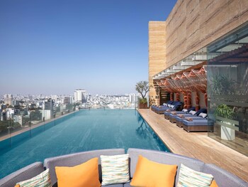 A high-rise building with multiple floors, featuring a rooftop bar with outdoor seating.