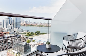 Un balcon moderne offrant une vue sur la ville, doté d’une porte vitrée et d’une table avec des chaises.