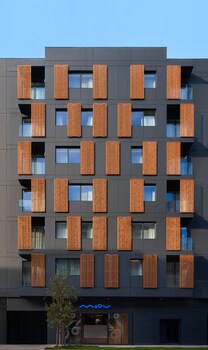 A modern building with multiple balconies, each with vertical wooden slats.