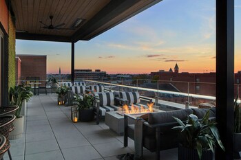 A rooftop terrace with outdoor seating, a fire feature, and a cityscape view.