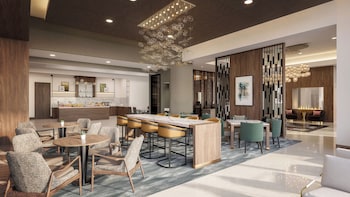 A modern lobby with a marble reception desk, a green sofa, and a unique chandelier.