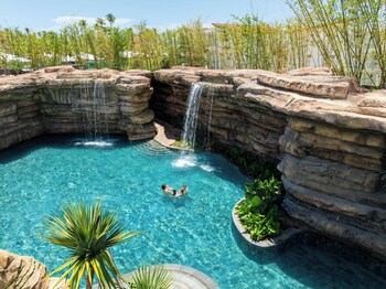 A resort with a swimming pool, a hot tub, and a bridge.